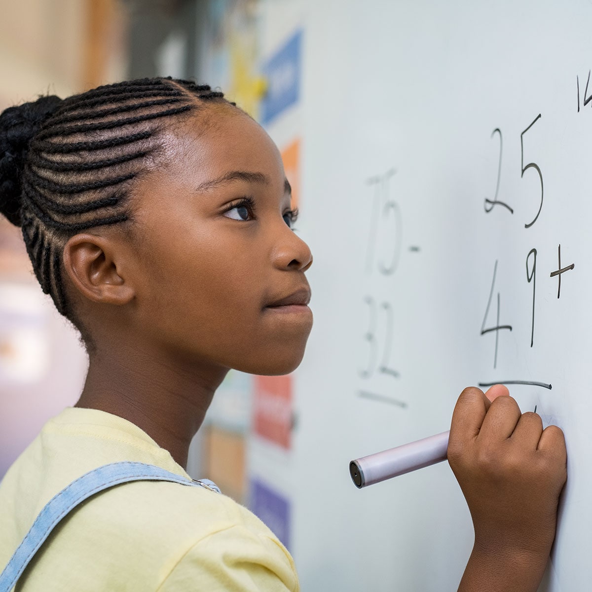 Young girl working a math problem at a whiteboard. 