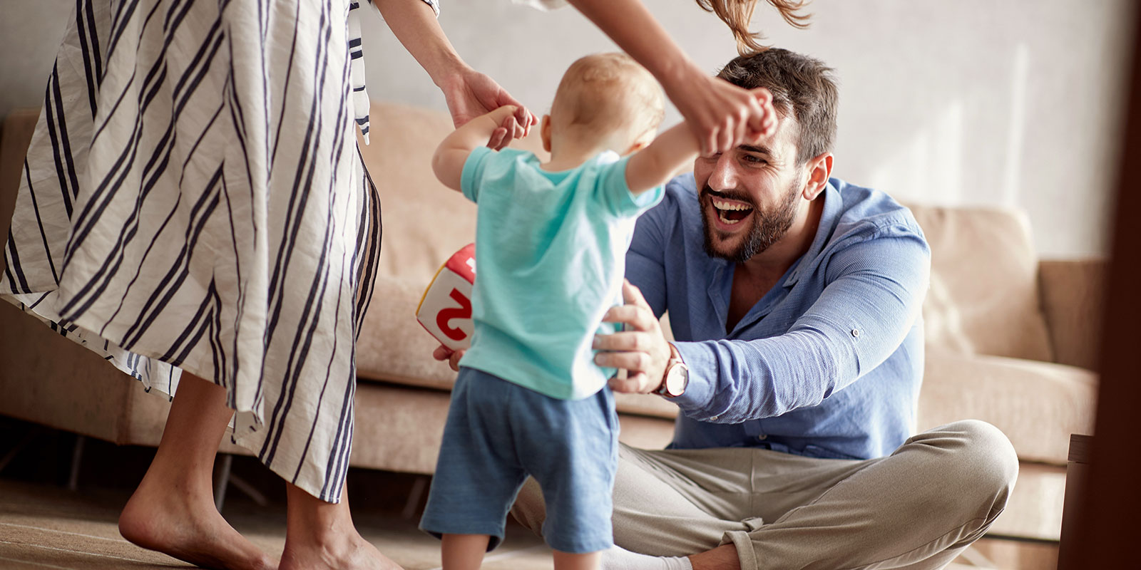 Mother and father helping their toddler walk. 