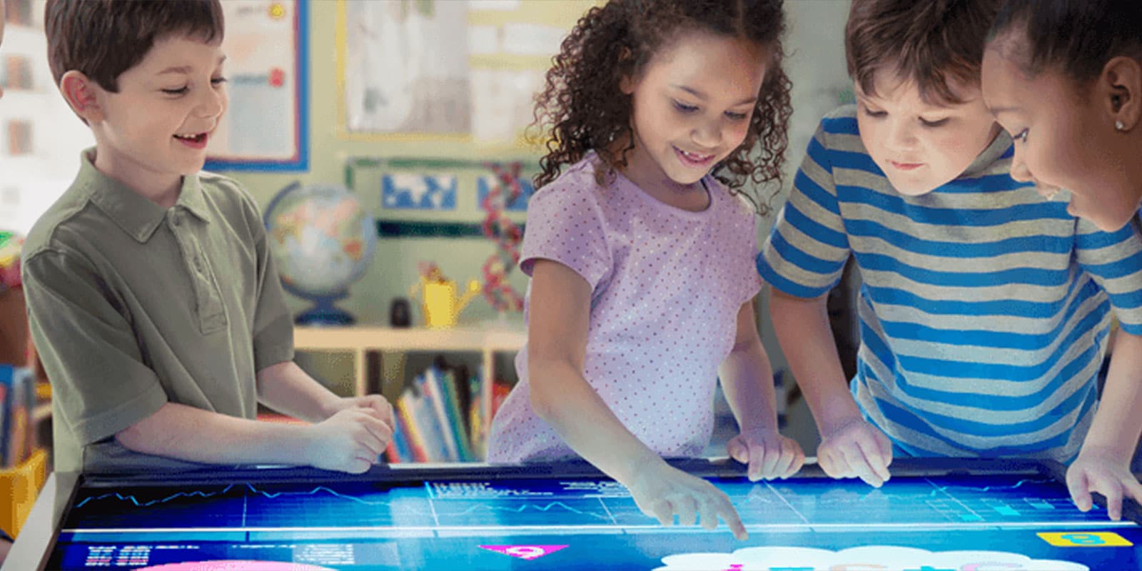 Young children working on a large, flat digital screen.