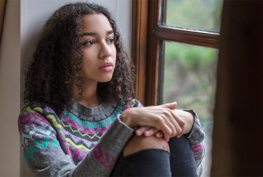 Female teenager thoughtful looking out of window