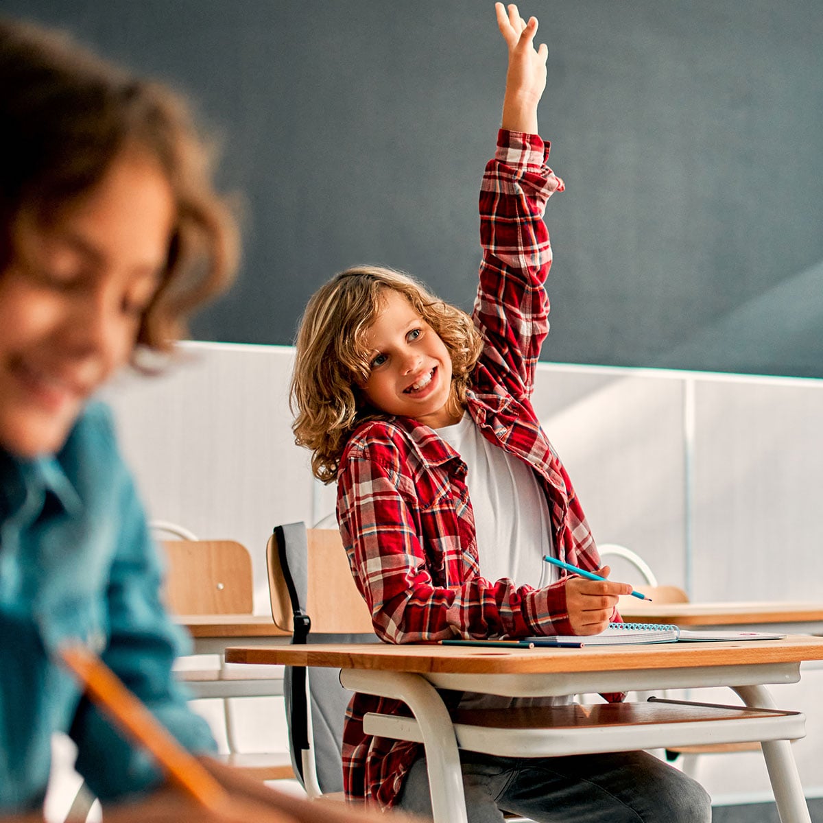 Student raising their hand in class. 