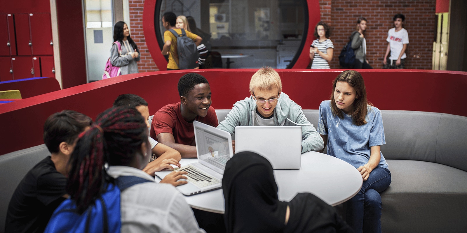 Image of students sitting at a table using laptop computers