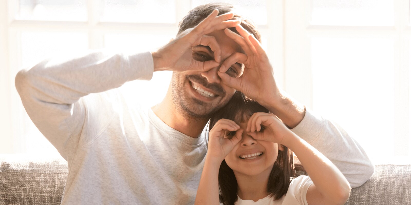 Young child and adult looking through curled fingers