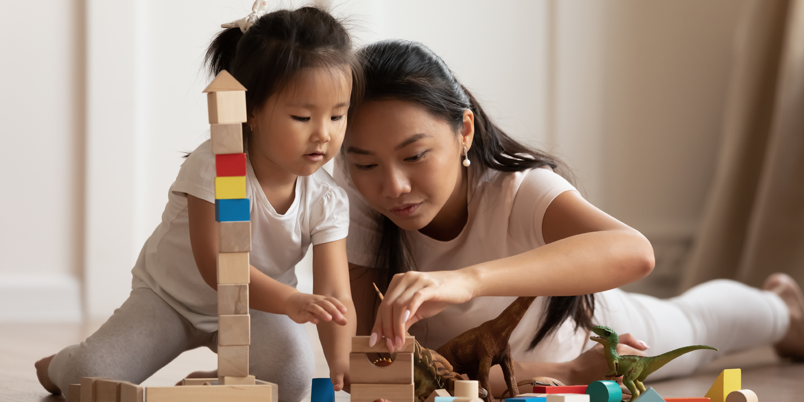 Mother and young daughter playing with blocks.