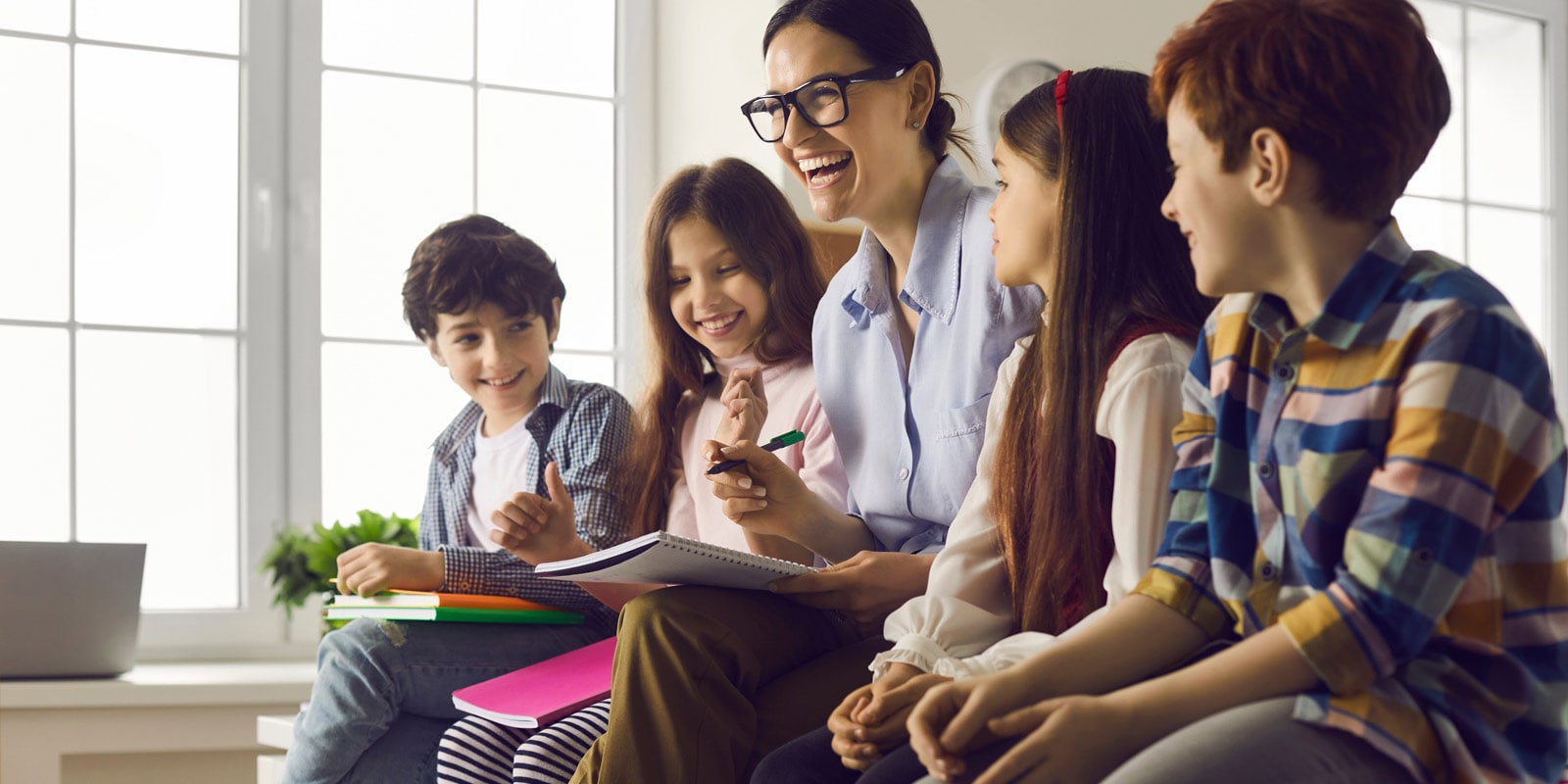 Teacher engaging with a group of smiling children during a classroom activity