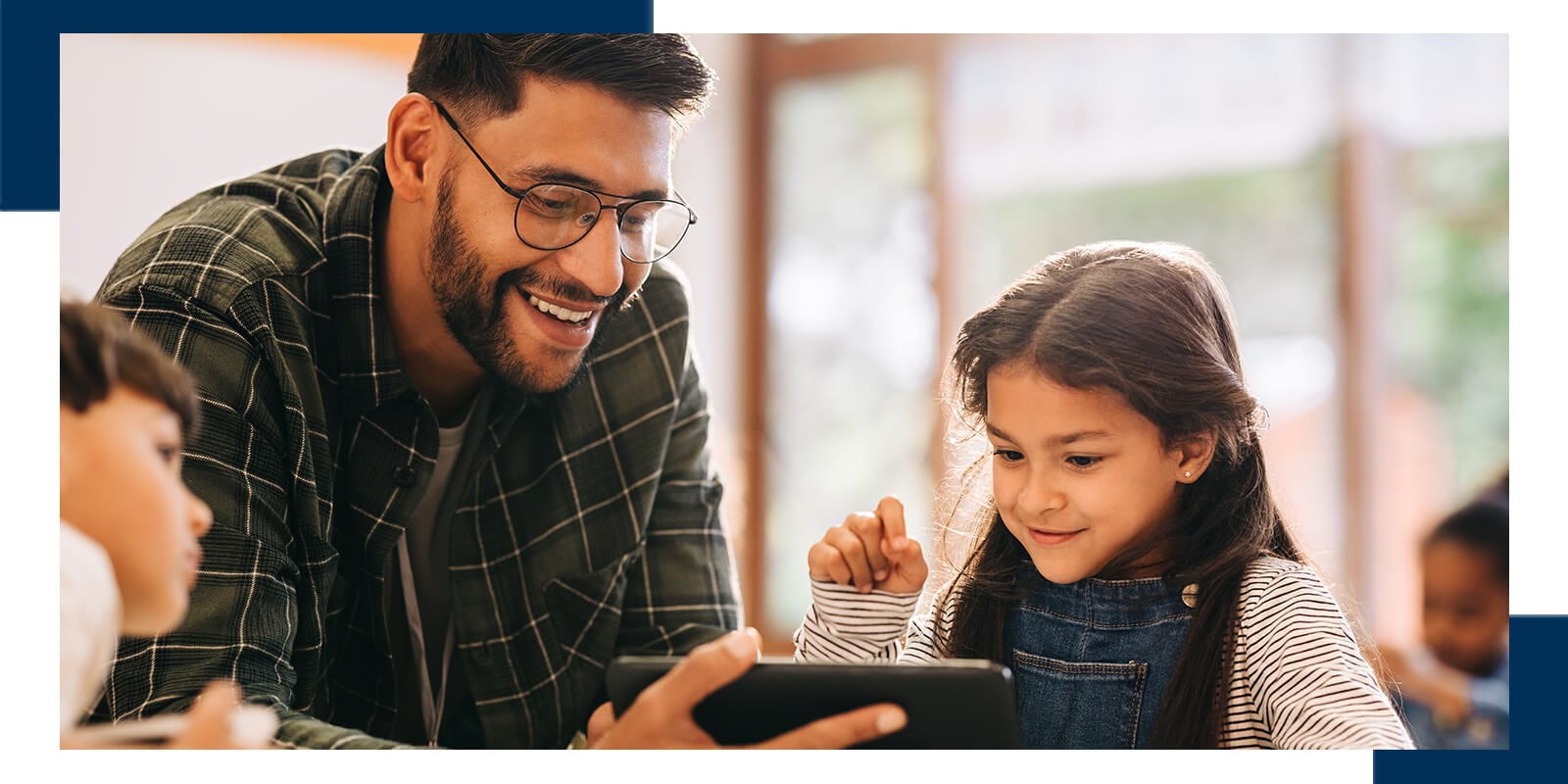 A man and a young girl sit at a table, interacting over a digital tablet in a warmly lit indoor setting.