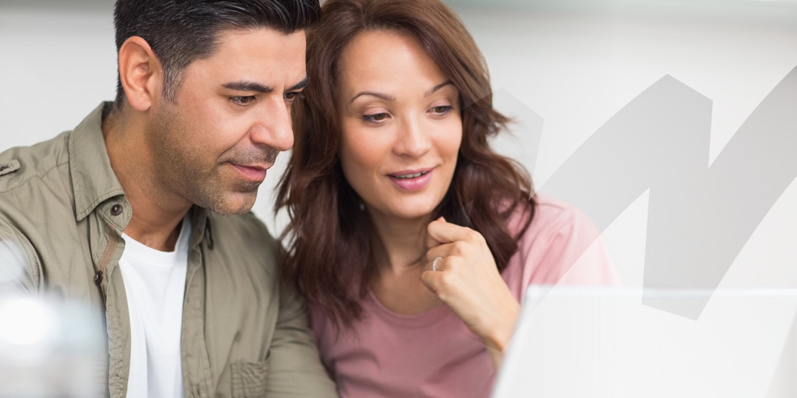 A man and a woman sit closely together, looking at a laptop screen with a rising graph, indicating a focus on data or analytics.
