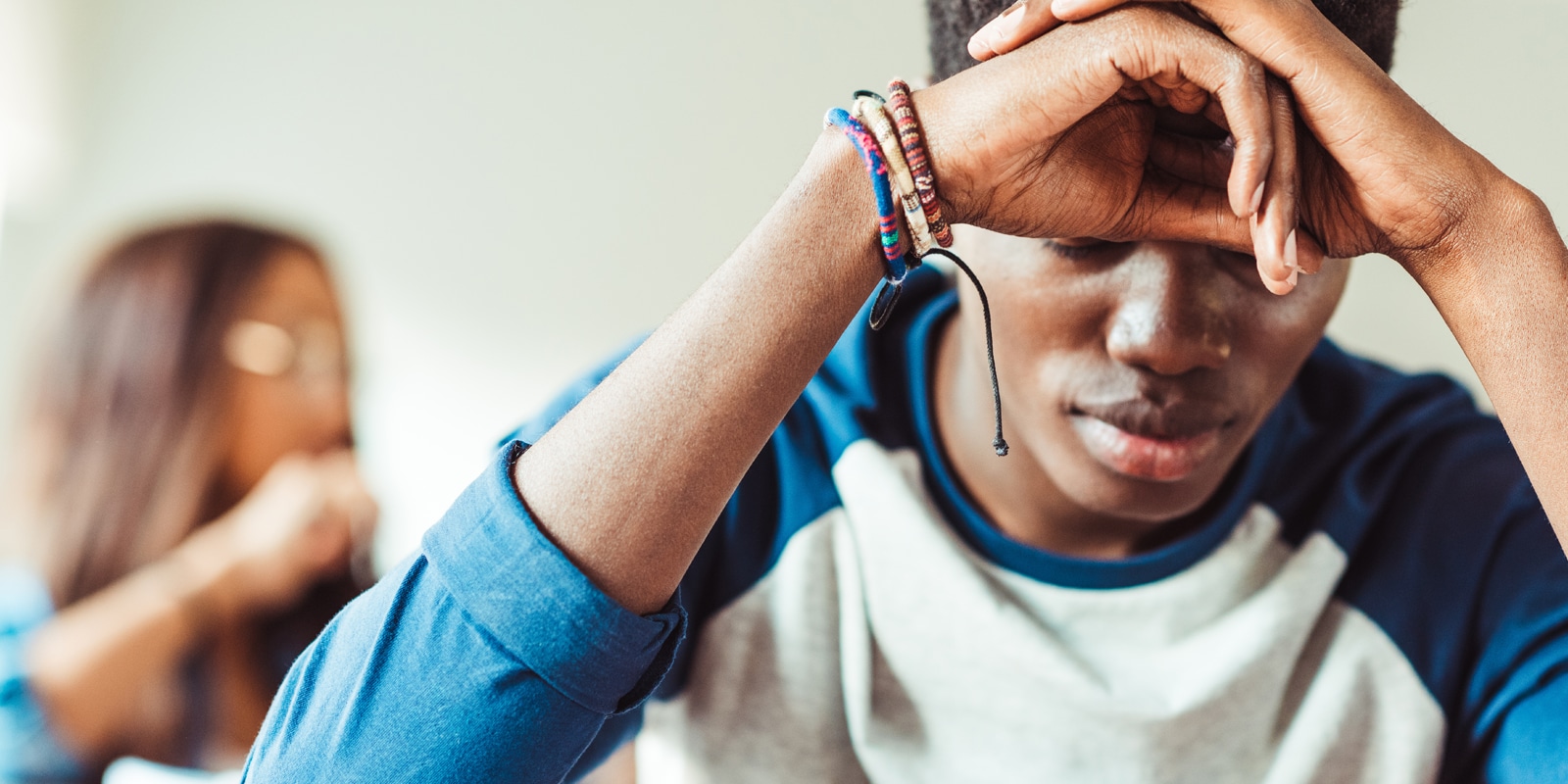 Youth looking down leaning head on hands