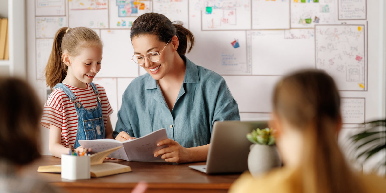 A teacher assisting a child with school work in class