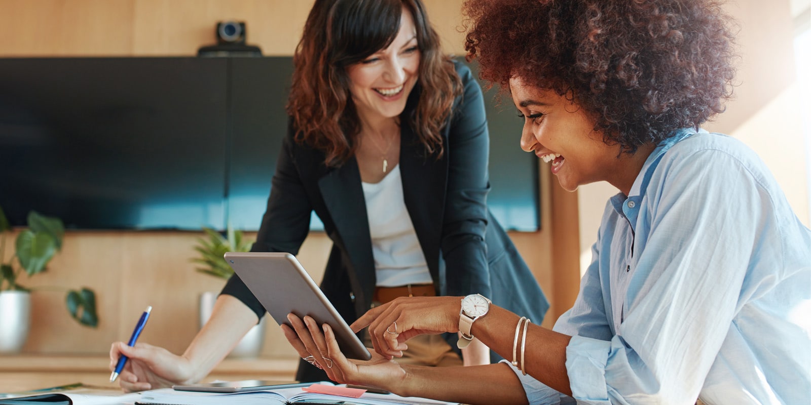 Creative female executives meeting in an office using tablet pc and smiling.