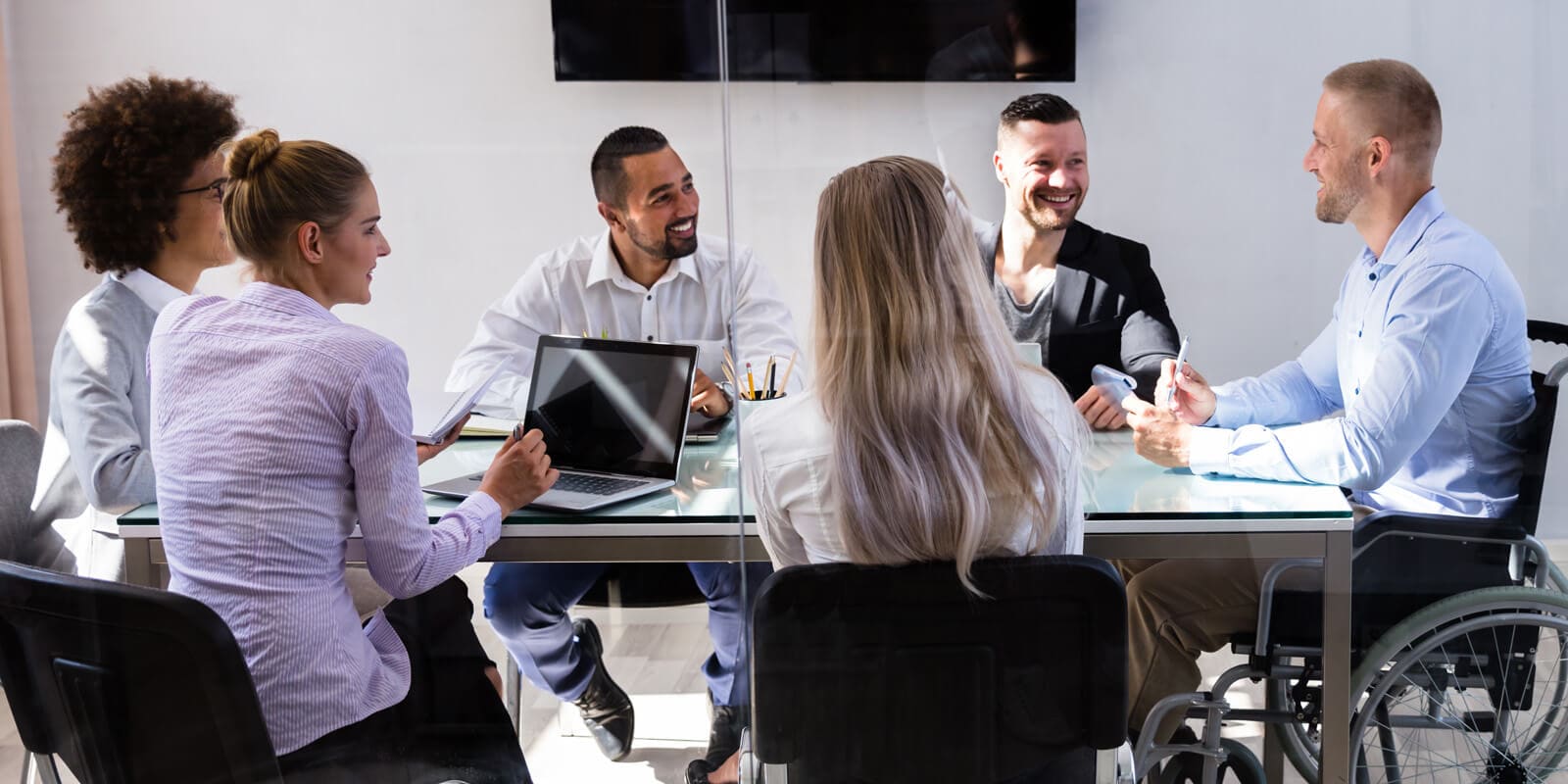 Disabled Male Manager Sitting With His Colleagues At Workplace