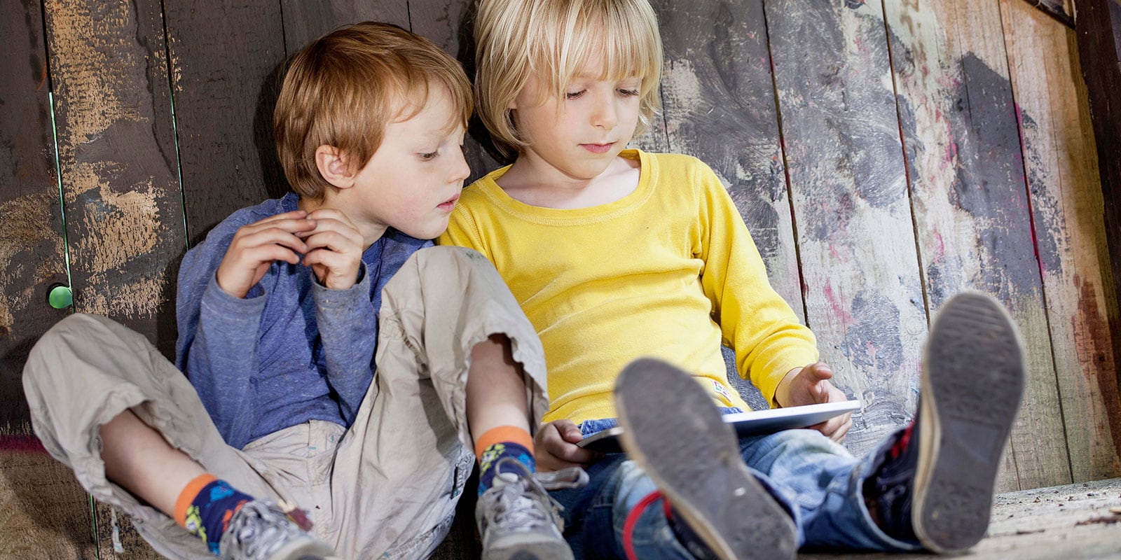 Two young kids looking on a tablet device.