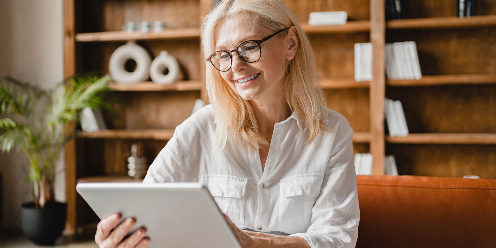 Successful confident mature businesswoman teacher psychologist using digital tablet for remote work, watching webinars, doing shopping online, surfing social media in office.