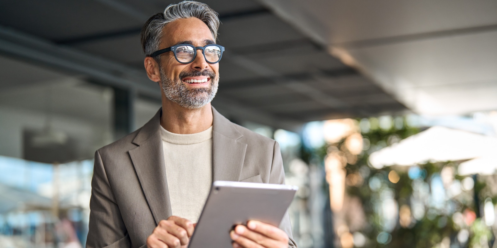 Adult male holding a tablet device and looking thoughtful.