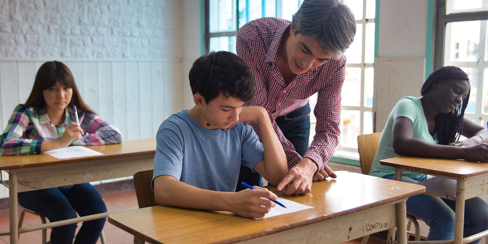 Male teacher working with a student in the classroom.