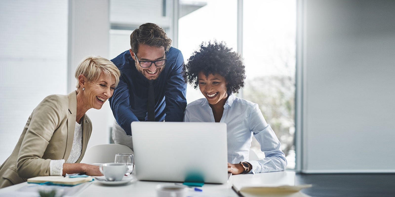 Three collegues in an office working on a laptop computer.
